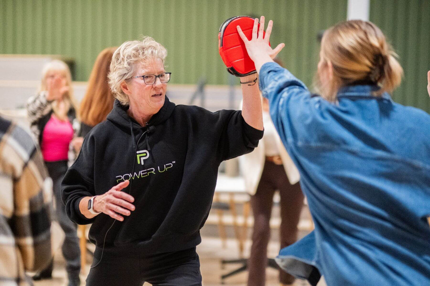 Lisa Davis demonstrating a defensive strike with a participant using a focus mitt
