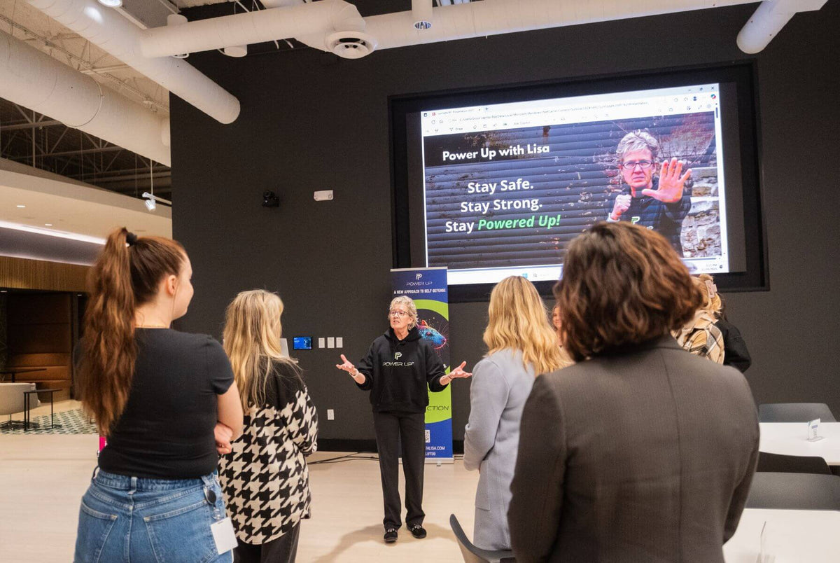 Employees gathered around a screen reading 'Stay Safe, Stay Strong, Stay Powered Up' during a workshop
