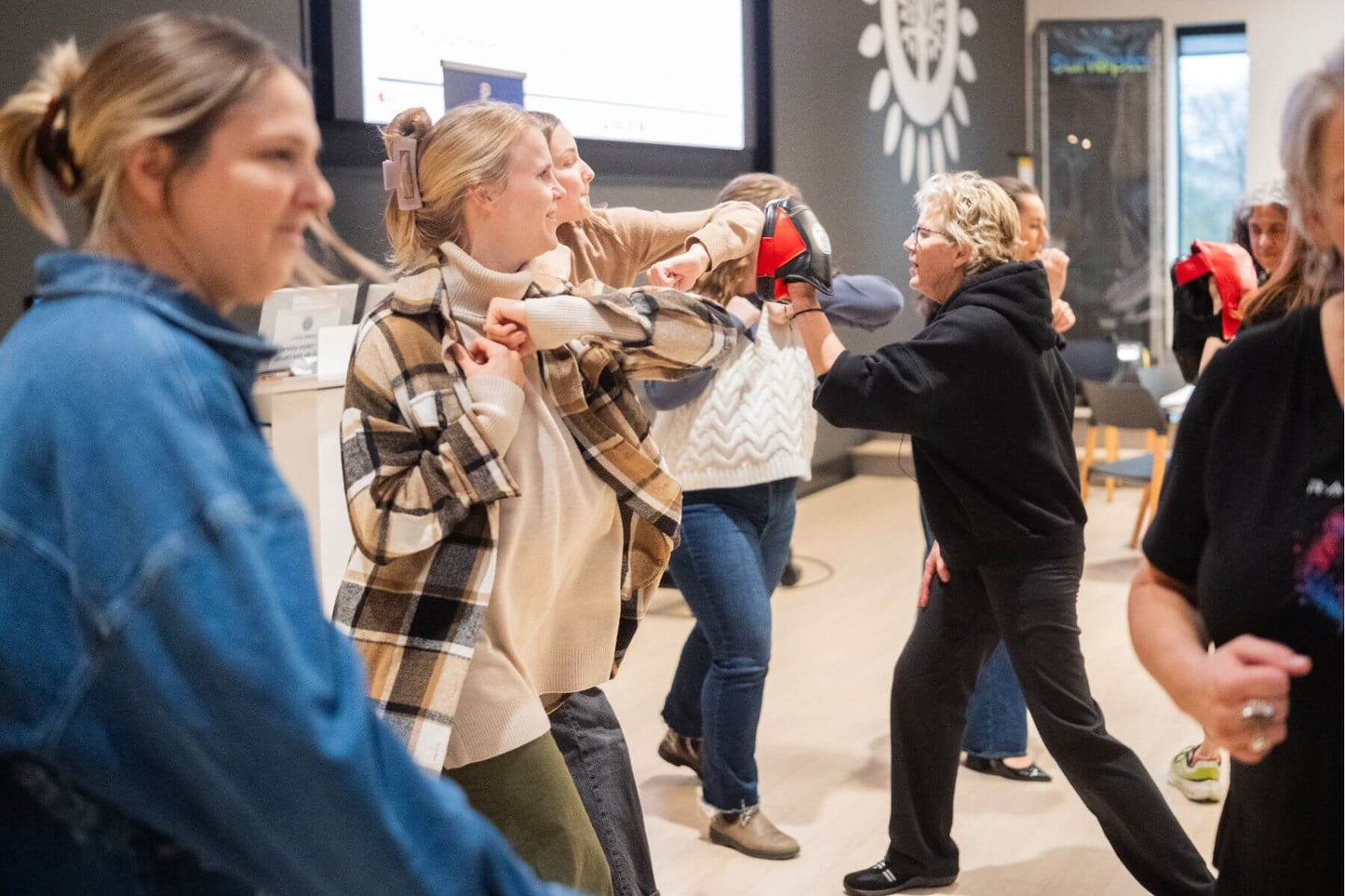 A group of people actively participating in a self-defense drill at a Power Up with Lisa class