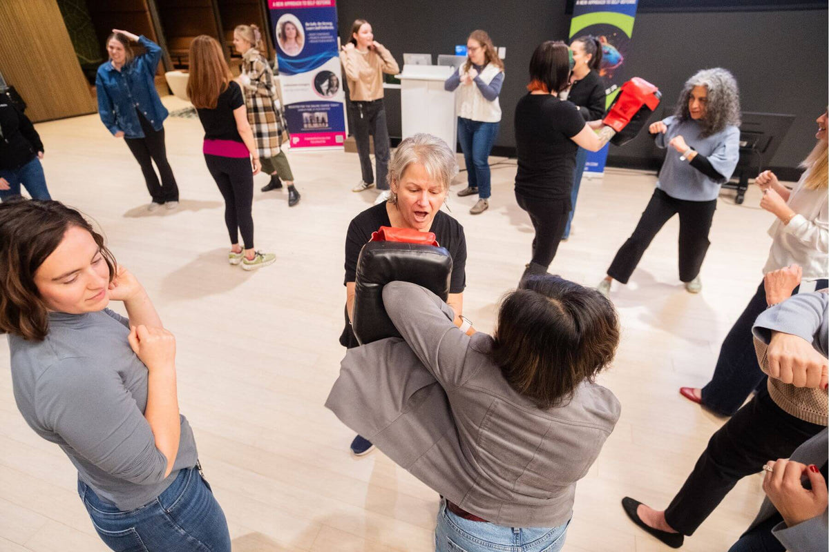 Employees in a self-defense class practicing elbow strikes with each other