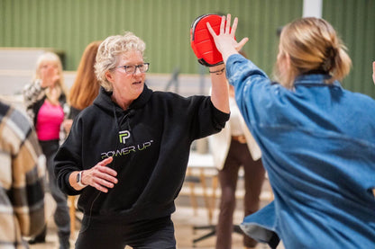 Lisa Davis demonstrating a defensive strike with a participant using a focus mitt