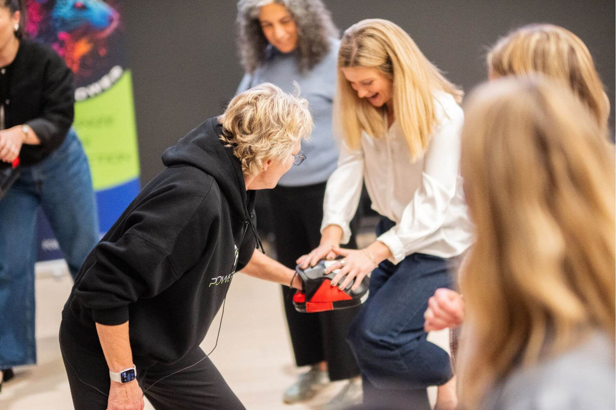 Lisa Davis assisting a participant on how to do a knee kick for self-defense