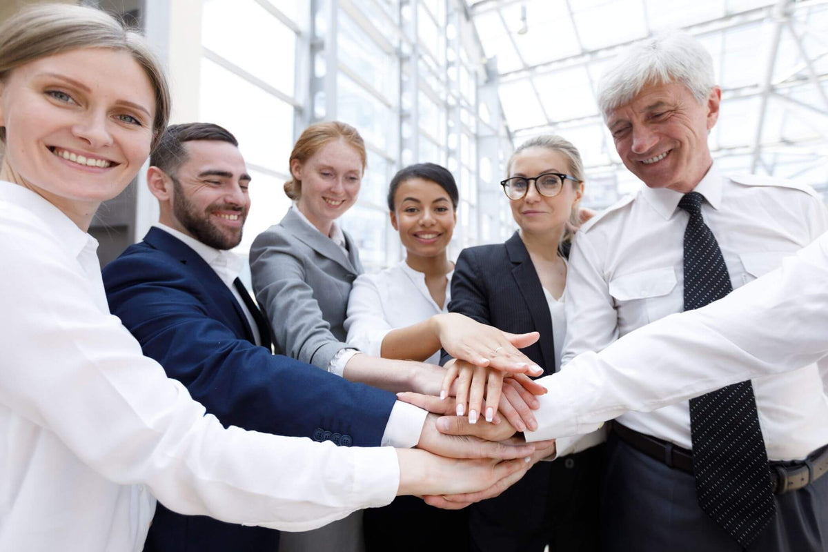 Group of business people with hands stacked together and smiling in an office