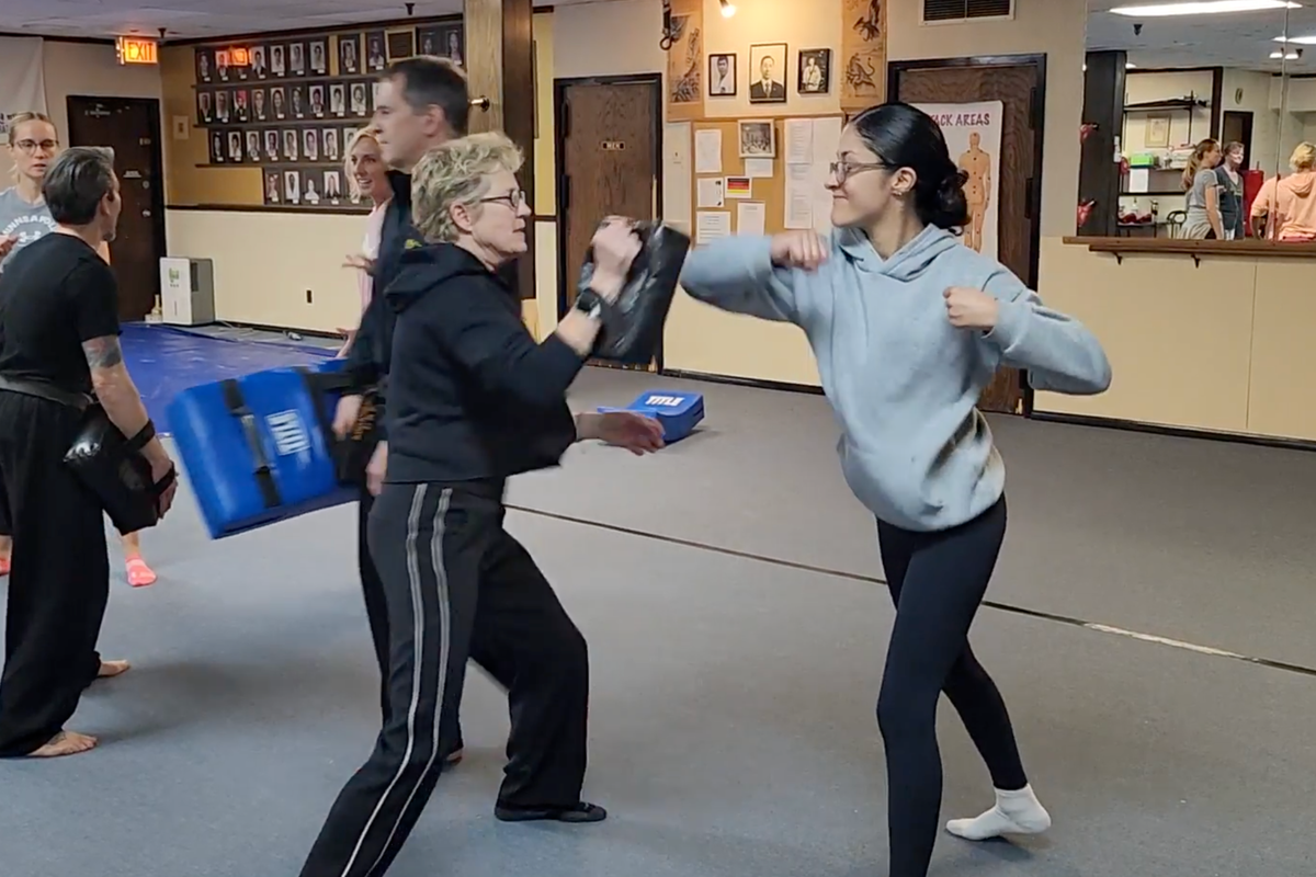 Lisa Davis helping a student with an elbow jab defense move