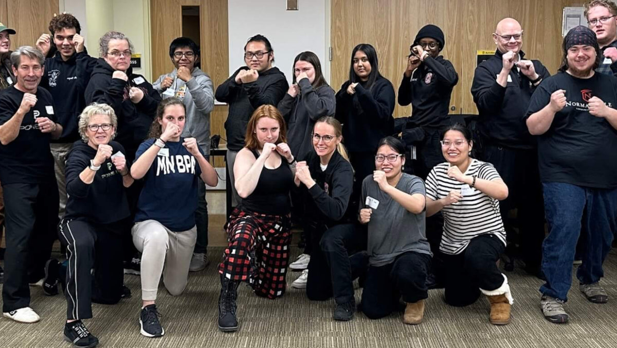 College students, campus safety officers, and Power Up with Lisa instructors in fighting stance after a campus self-defense class