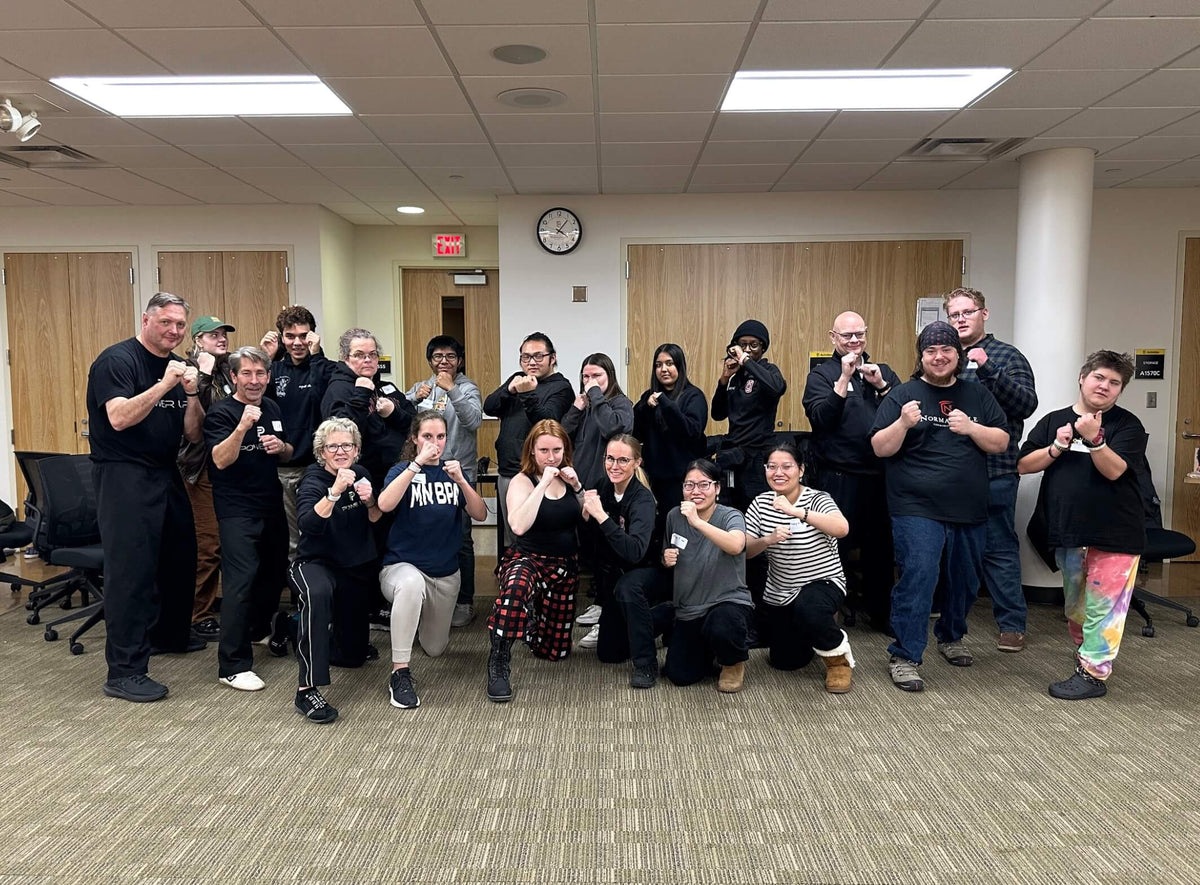 College students, campus safety officers, and Power Up with Lisa instructors in fighting stance after a campus self-defense class