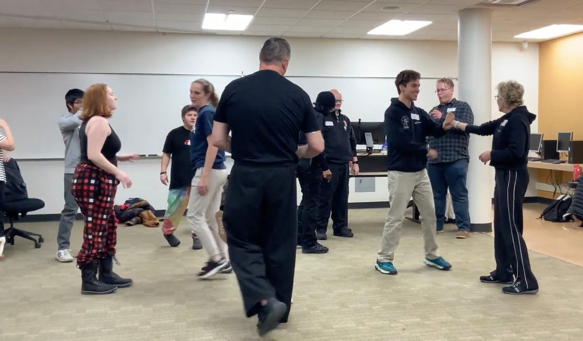 Lisa Davis coaching a college student through a wrist grab escape as the class practices