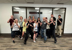 A group of people smiling and posing a self-defense move after a class