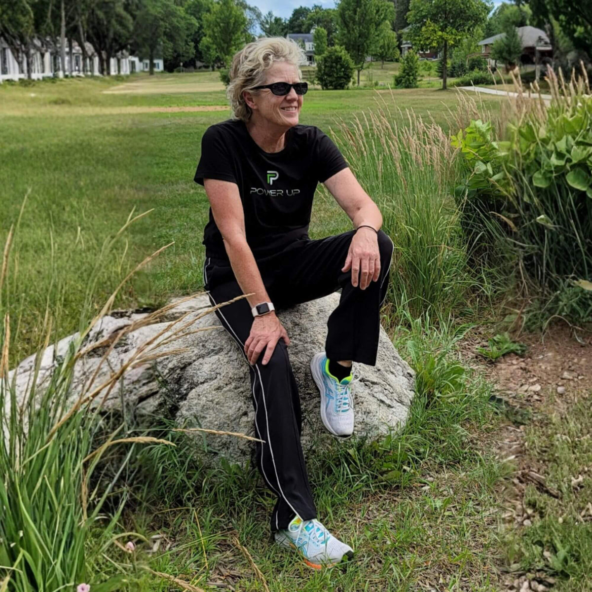 Lisa Davis, founder of Power Up with Lisa, sitting outside on a rock smiling