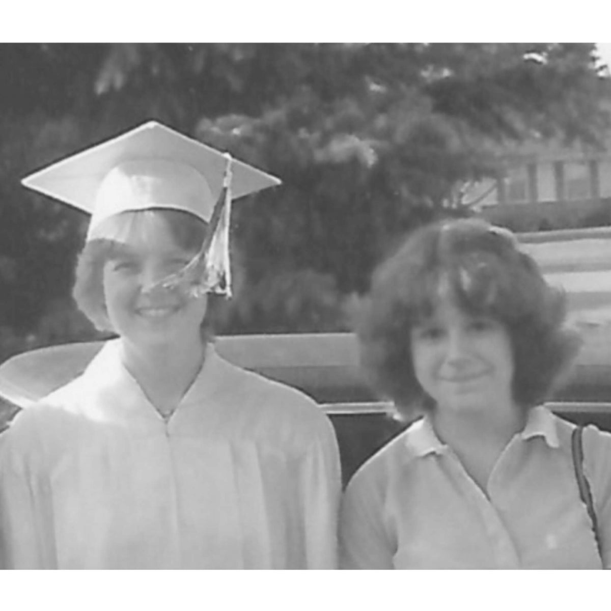 Lisa Davis wearing a cap & gown for her graduation, posing with her sister in 1981