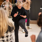 Lisa Davis demonstrating a knee kick movement in front of an audience.