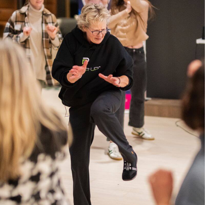 Lisa Davis demonstrating a knee kick movement in front of an audience.